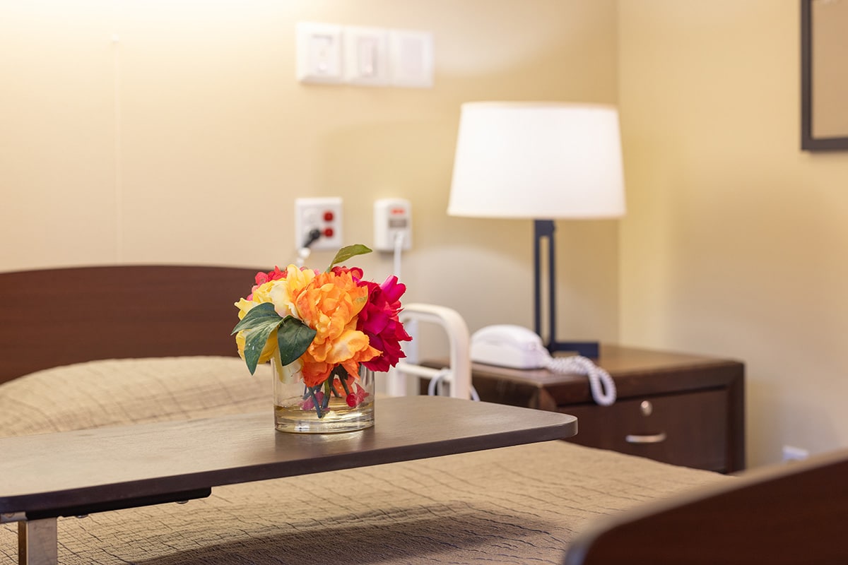 A resident's bedside with flowers at Pine Ridge