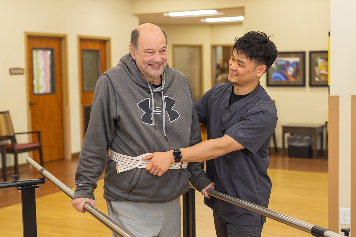 A physical therapist helping a man walk at Pine Ridge